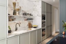 a chic contemporary kitchen with light grey no hardware cabinets, a white marble backsplash and countertops, built-in lights