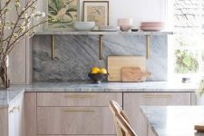 a chic contemporary kitchen with neutral cabinets, a grey kitchen backsplash and countertops and touches of gold for more chic