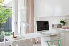 a chic neutral home office with a white storage unit that takes the whole wall, a desk and a mint chair