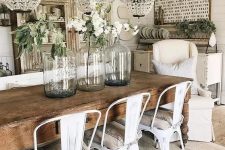 a chic vintage farmhouse dining area with crystal chandeliers, a sign, a shabby chic buffet, a wooden table and metal chairs