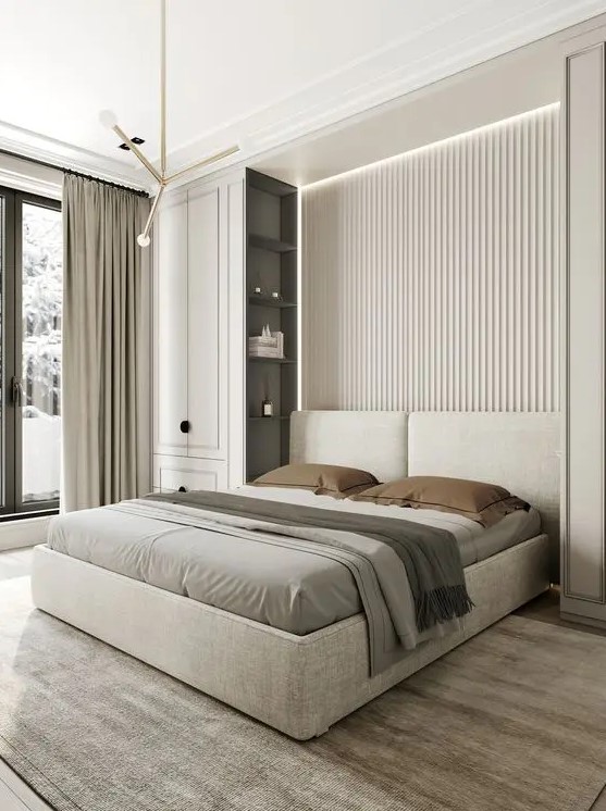 a clean contemporary bedroom with a neutral slab accent wall, an upholstered bed, two tall storage units, built in lights and pendant lamps