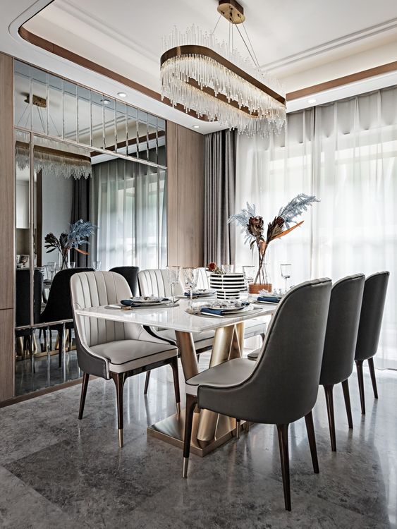 a contemporary and luxurious dining room with a white and gold table, grey and white chairs, a crystal chandelier over them