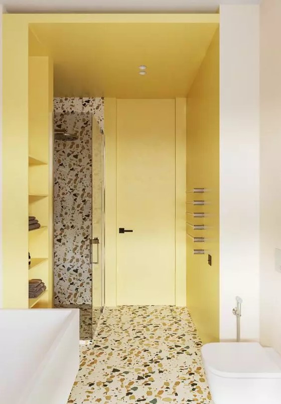 a contemporary bathroom with light yellow walls and shelves, a terrazzo floro and an accent wall in the shower and white appliances