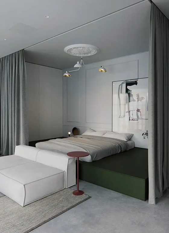 a contemporary bedroom with a bed on a green platform, a statement artwork, a soft white sofa and curtains to hide the bed and get more privacy