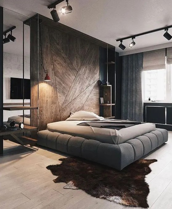 a contemporary bedroom with a wooden accent wall, a grey upholstered bed, spotlights, neutral textiles and an animal skin rug