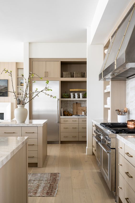 a contemporary blonde wood kitchen with sleek cabinets and neutrla stone countertops, stainless steel appliances