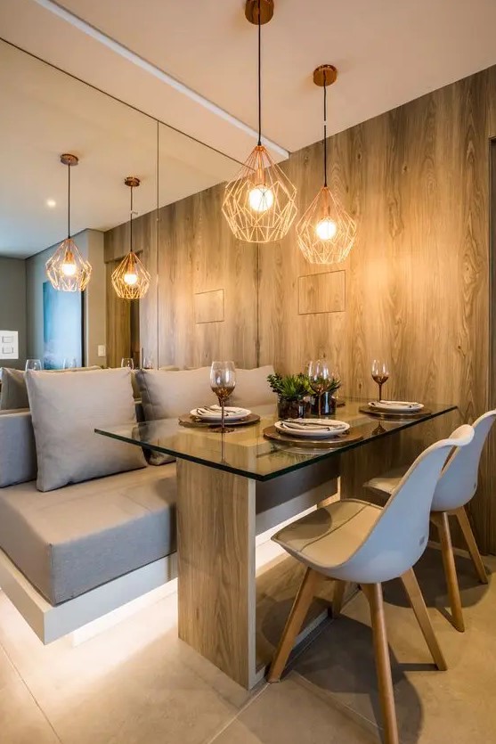 a contemporary dining nook with a mirror wall, a built in and lit up upholstered bench, a wood and glass table and white chairs