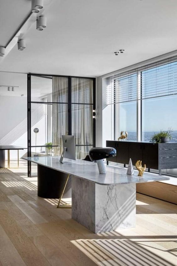 a contemporary home office with a sea view, a white marble desk, a cool chair, a black sideboard and a catchy table lamp