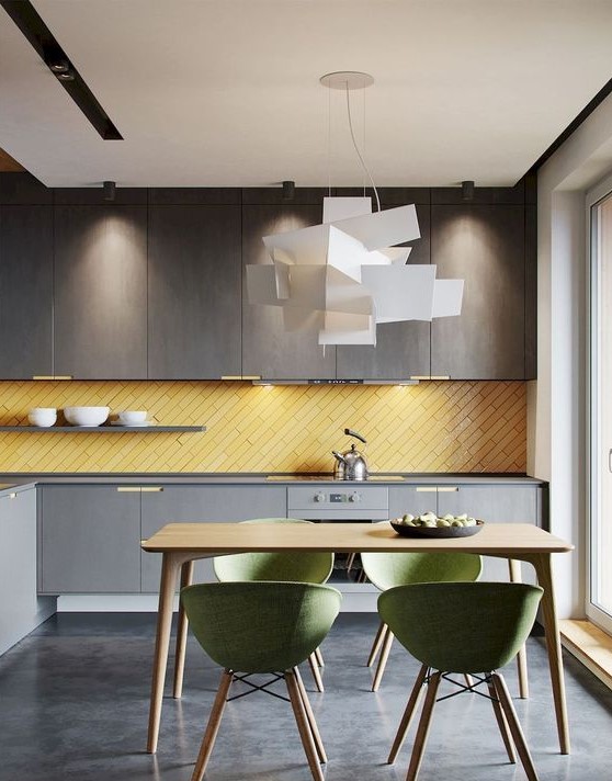 a contemporary kitchen with grey cabinetry of different shades, a yellow skinny tile backsplash and green chairs