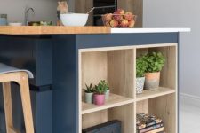 a contemporary kitchen with stained cabinets, a large navy kitchen island with wooden countertops and open shelves for storage
