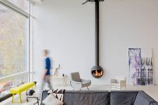 a contemporary living room with a glazed wall, a grey low sofa, a suspended hearth, some pretty furniture is very cool