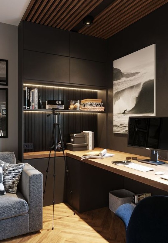 a contemporary moody home office with closed and open storage units, built in lights, a large desk and upholstered chairs