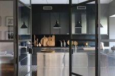a contemporary moody kitchen with ploished metal cabinets, a black backsplash and countertops plus black pendant lamps