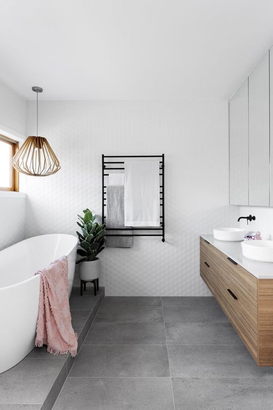 a contemporary neutral bathroom with white and concrete tiles, an oval bathtub, a floating vanity, black fixtures and a large mirror