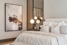 a contemporary neutral bedroom with a creamy bed, nightstands, a leather bench sphere pendant lamps and a round chandelier
