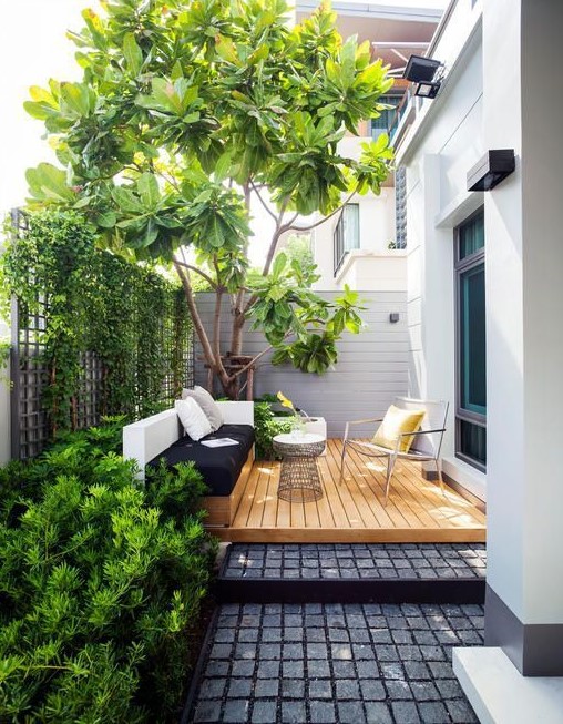 a contemporary terrace with a built-in bench in black and white, a deck, a comfy chair and a coffee table