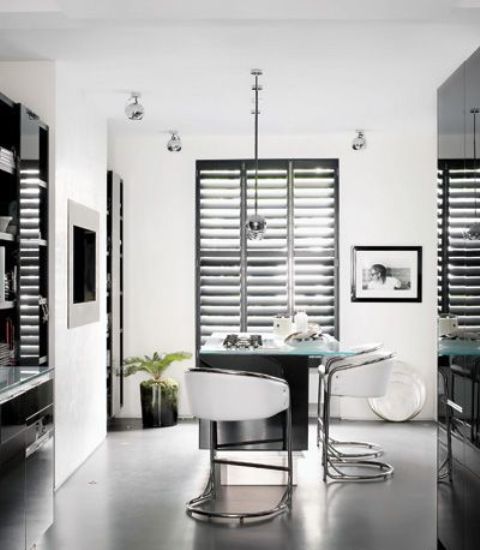 a contemporary with black cabinets, black shutters, a kitchen island that doubles as a table and white stools