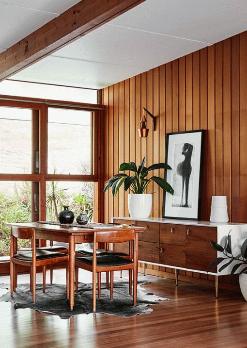 a cool mid-century modern dining room with lots of stained wood, a chic credenza, a stained table and chairs, potted plants