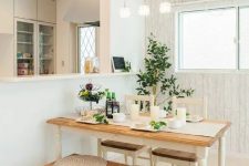 a cozy small dining space wiht a vintage table, chairs and a bench, potted greenery, a trio of pendant lamps