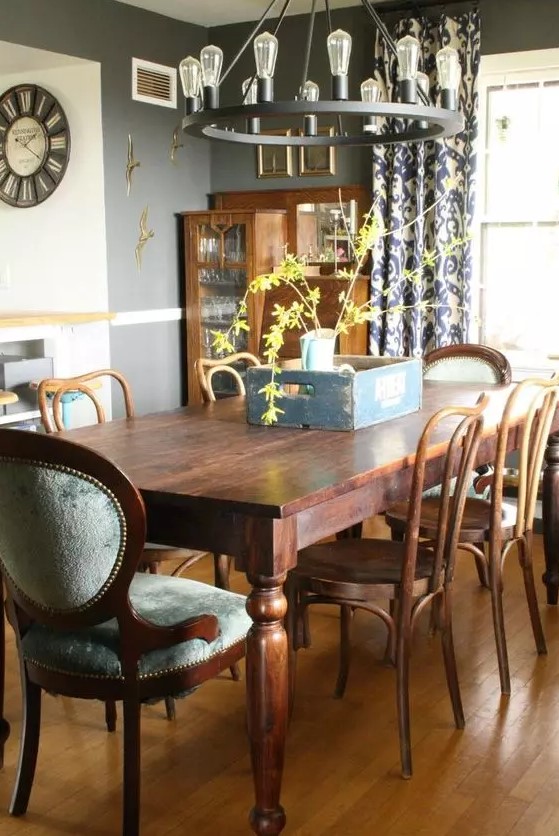 a cozy vintage dining room with a stained buffet, a dining table and grey upholstered and just stained chairs plus a round chandelier