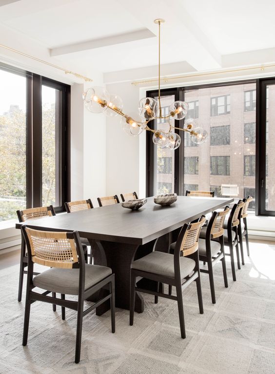 a fab contemporary dining room with a black table, chairs with woven backs, a lovely chandelier with bubbles