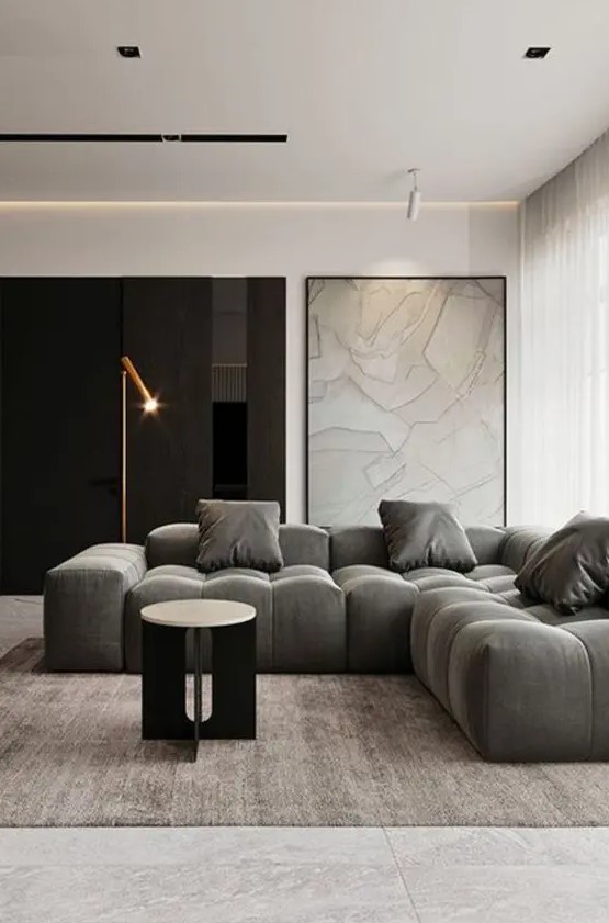a fabulous contemporary living room in a monochromatic color palette, a lovely low sectional, a round table, a floor lamp and a map in a frame