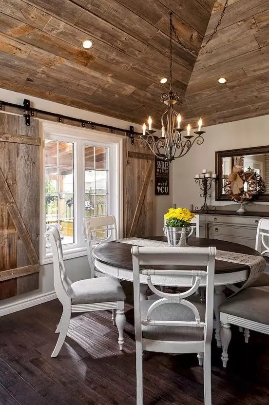 a farmhouse wooden dining area with shutters, vintage white furniture and a framed mirror
