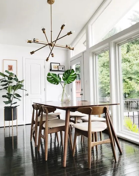 a fresh and light-filled mid-century modern dining space with a stained table, white chairs, a gold chandelier and potted plants