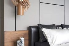 a gorgeous contemporary bedroom with a grey panel accent wall, a black leather bed, contrasting bedding, a floating nightstand and a jaw-dropping pendant lamp