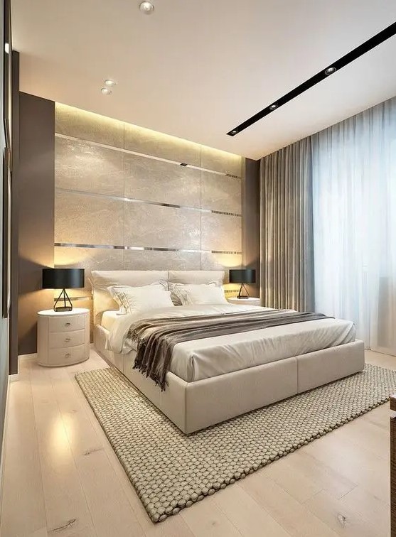 a gorgeous contemporary bedroom with a tile and metallic line accent wall, a neutral upholstered bed, round white nightstands, black lamps and several layers of light