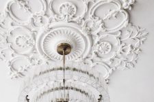 a gorgeous white ceiling medallion and a clear crystal chandelier with a modern design that doesn’t distract attention from it