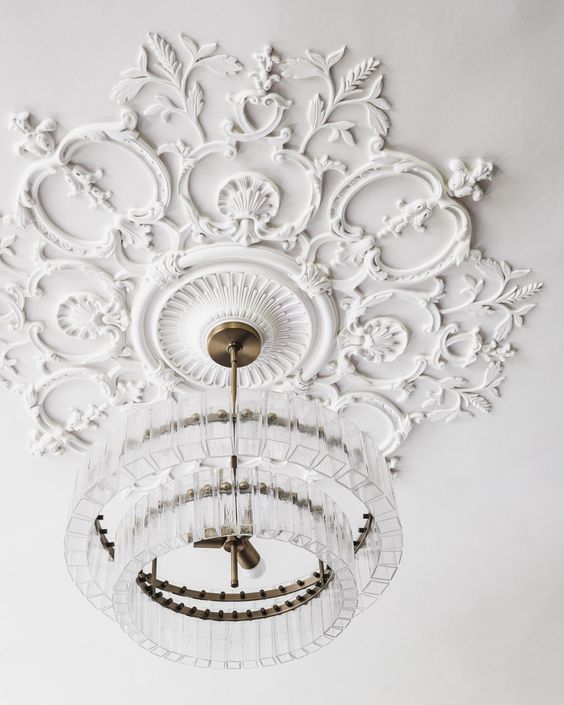 a gorgeous white ceiling medallion and a clear crystal chandelier with a modern design that doesn't distract attention from it