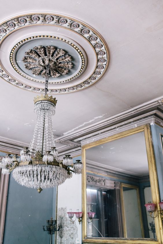 a large and bold ceiling medallion with light blue and copper touches, with beautiful shapes and lines and a large crystal chandelier