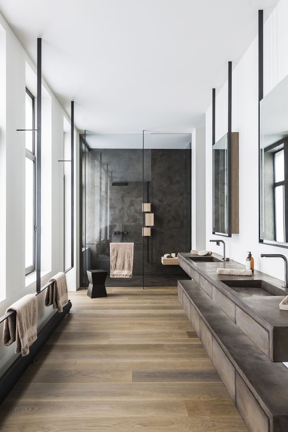 a large contemporary bathroom with a stained floor, a large double vanity, a black shower space and black fixtures wows