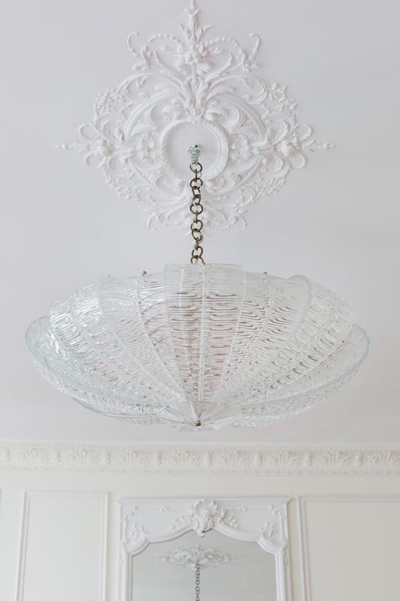a lovely small ceiling medallion is a pretty decoration and a large round crystal lamp on chain that contrasts it a lot