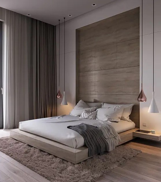 a luxurious contemporary bedroom done in warm neutrals, with a wood clad niche and a matching bed, neutral textiles and cool pendant lamps