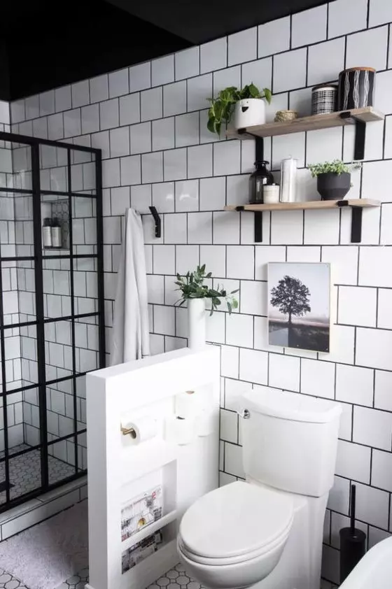 a modern neutral bathroom clad with white square tiles, with a French glass shower space, a pony wall to separate the toilet