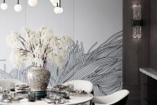 a monochromatic dining room with a statement wall, a round table and creamy chairs, a lovely black and bubble chandelier