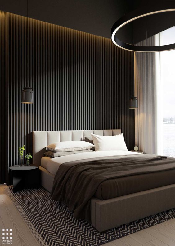 a moody contemporary bedroom with a black slat wall, a grey upholstered bed, black nightstands, a round chandelier and pendant lamps