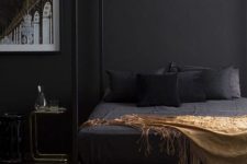 a moody contemporary bedroom with black walls, a black cnaopy bed, chic nightstands and a bold artwork