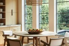a neutral chic dining room with sleek stained storage units, a round table, some elegant chairs and a woven pendant lamp plus a gorgeous view
