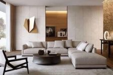 a neutral contemporary living room done in light greys, with a corner sofa, a daybed, a wooden chair, a round table, built-in lights