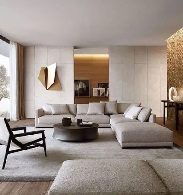 a neutral contemporary living room done in light greys, with a corner sofa, a daybed, a wooden chair, a round table, built in lights