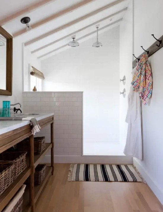 a neutral farmhouse bathroom clad with white subway tiles and a pony wall that separates the shower from the rest of the space