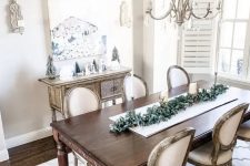 a neutral shabby chic dining room with an elegant inlay console, a dark stained table and chic chairs, a crystal chandelier