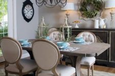 a neutral vintage dining space with grey walls, a large vintage credenza, a stained dining table and vintage chairs with neutral upholstery, a vintage metal chandelier
