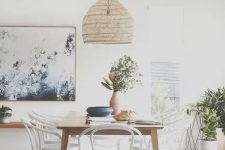 a pretty Scandinavian dining room with a sleek table, white and stain matching chairs, a woven pendant lamp and potted plants