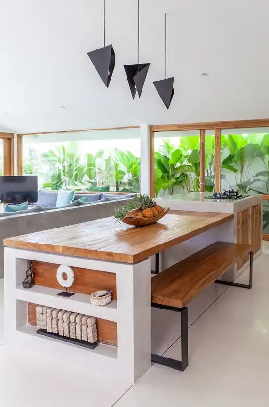 a pretty contemporary kitchen in white, with stained wood and a glazed wall that opens on a tropical garden