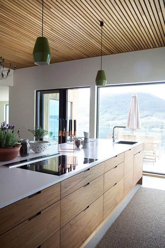 a pretty contemporary kitchen with a light stained kitchen island, a wooden slab ceiling and grene pendant lamps