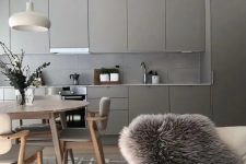 a pretty greige kitchen with sleek cabinets and a concrete tile backsplash, a neutral and cozy dining space here